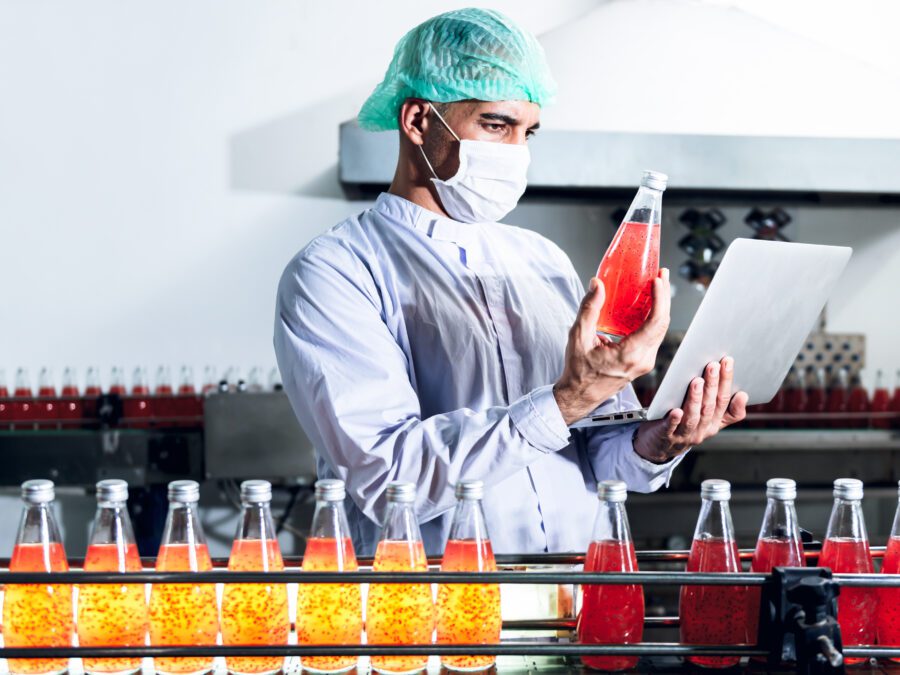 Nutritionist in lab comparing bottled beverage to food formulation software on computer