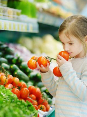 Little girl choosing tomatoes in a food store